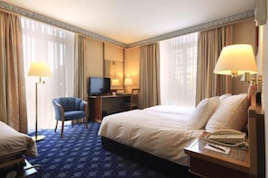 A hotel room with a bed, desk, chair, television, and lamps. - Hotel Mirabeau, BW Signature Collection (Lausanne)