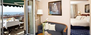Een hotelkamer met balkon, een bank, een bed en een schilderij.