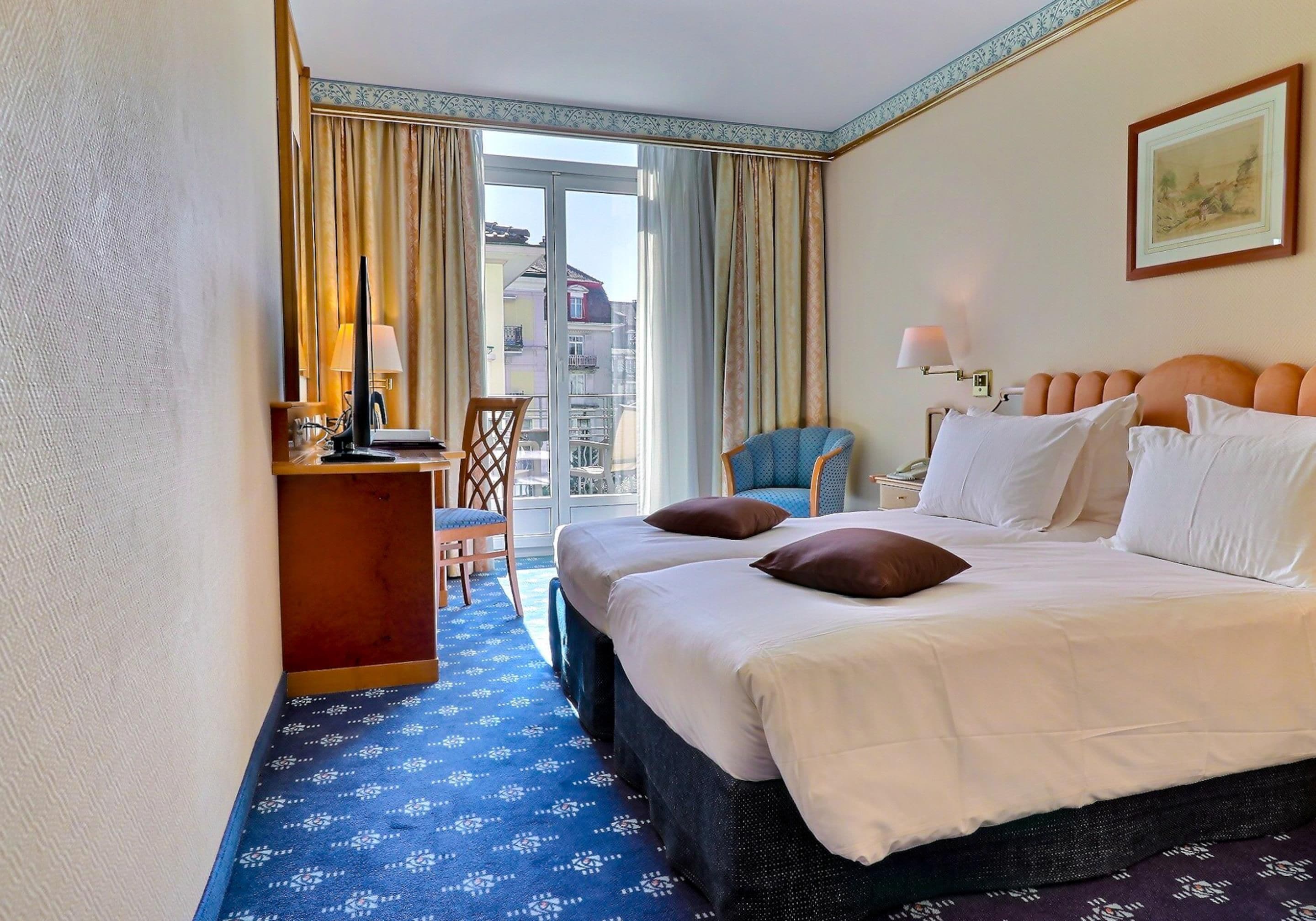 Ein Hotelzimmer mit Bett, Schreibtisch, Stuhl und Blick nach draußen.