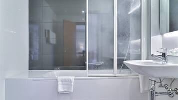 A modern bathroom with a bathtub, a sink, and a window with condensation.
