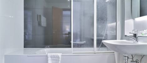 Ein modernes Badezimmer mit einer Badewanne, einem Waschbecken und einem Fenster mit Kondensation.