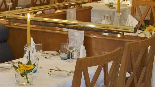 A restaurant interior with tables set for dining, candles, and a menu board.