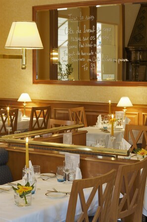 Interior de restaurante con mesas preparadas para comer, velas y un tablero de menú.