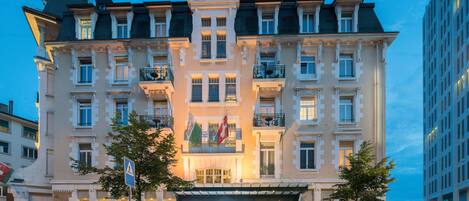 Un hotel de varios pisos con un diseño arquitectónico clásico, con balcones y una entrada destacada.