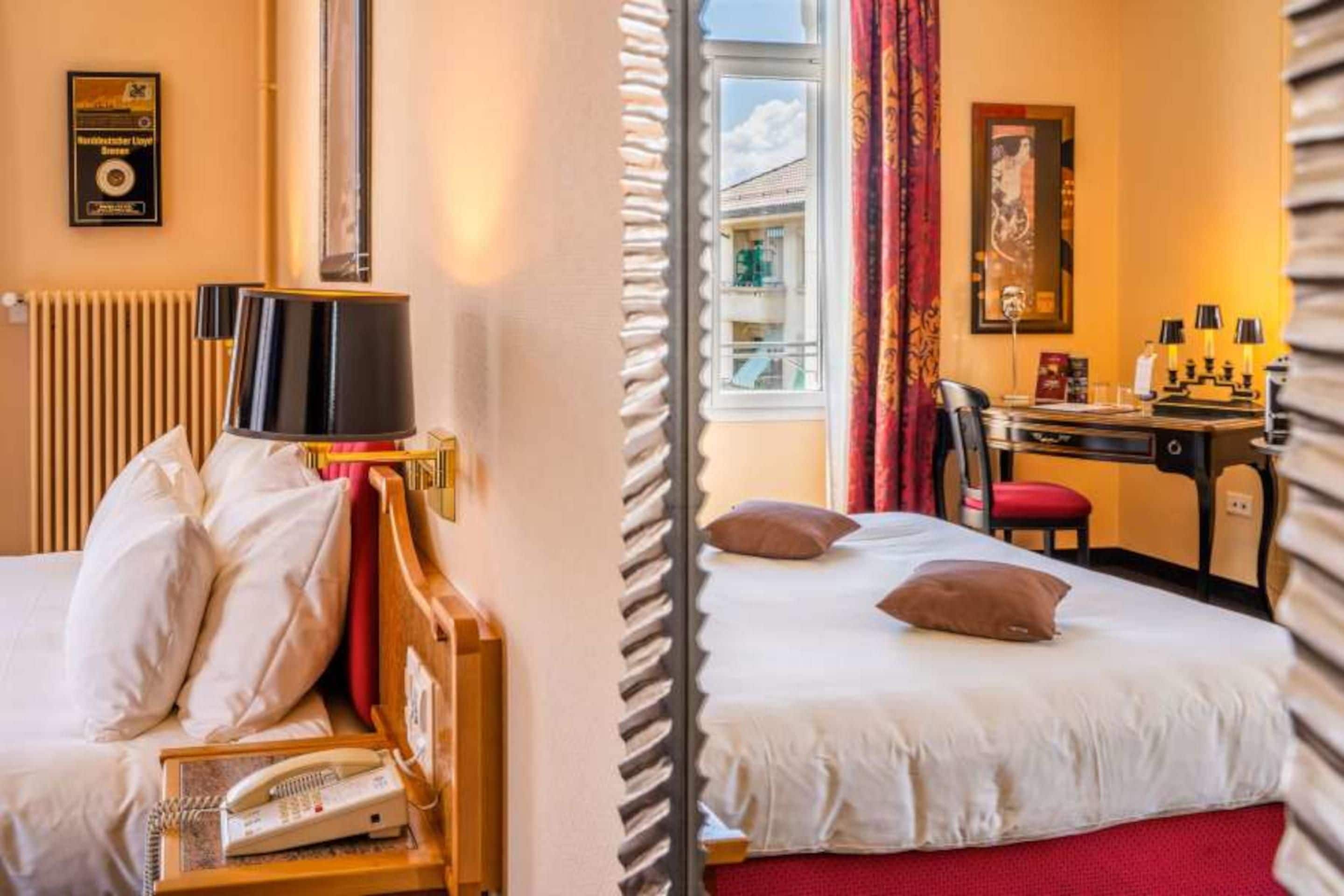 A hotel room with a bed, a desk, a chair, a telephone, and a window with curtains.