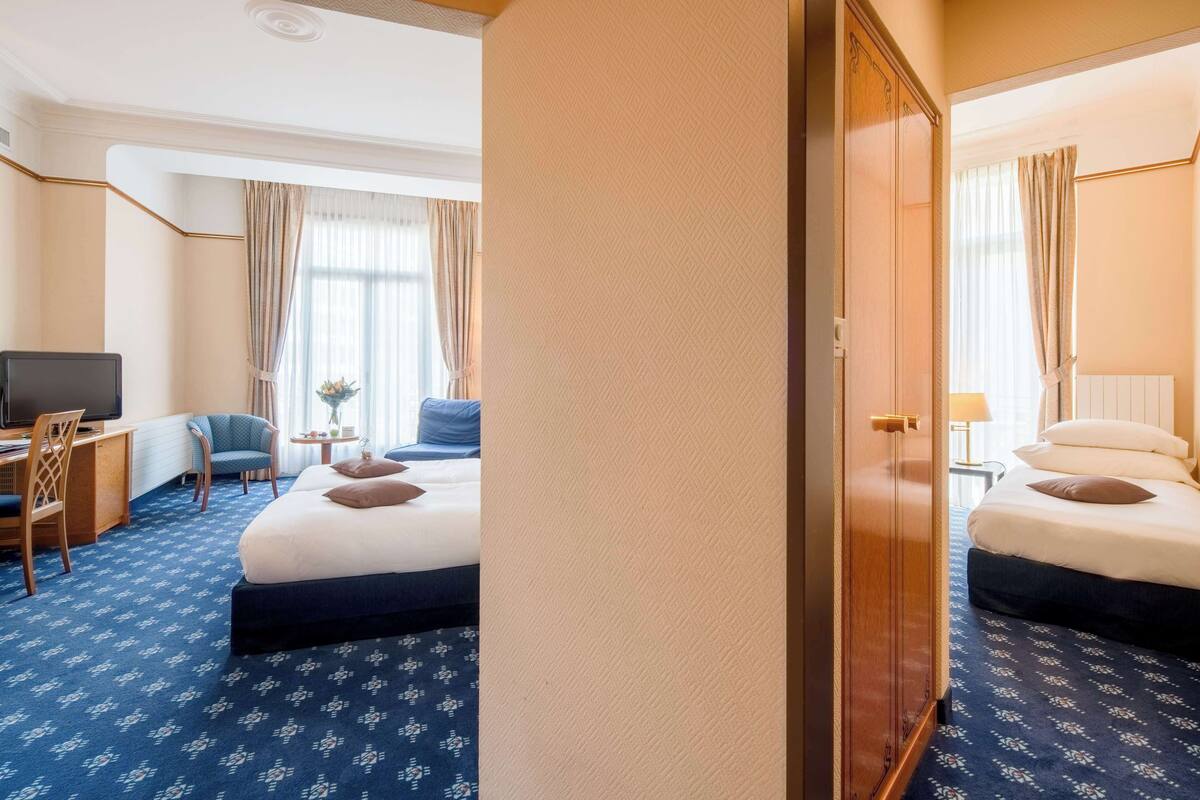 Une chambre d’hôtel avec deux lits, un bureau, une chaise et un téléviseur.