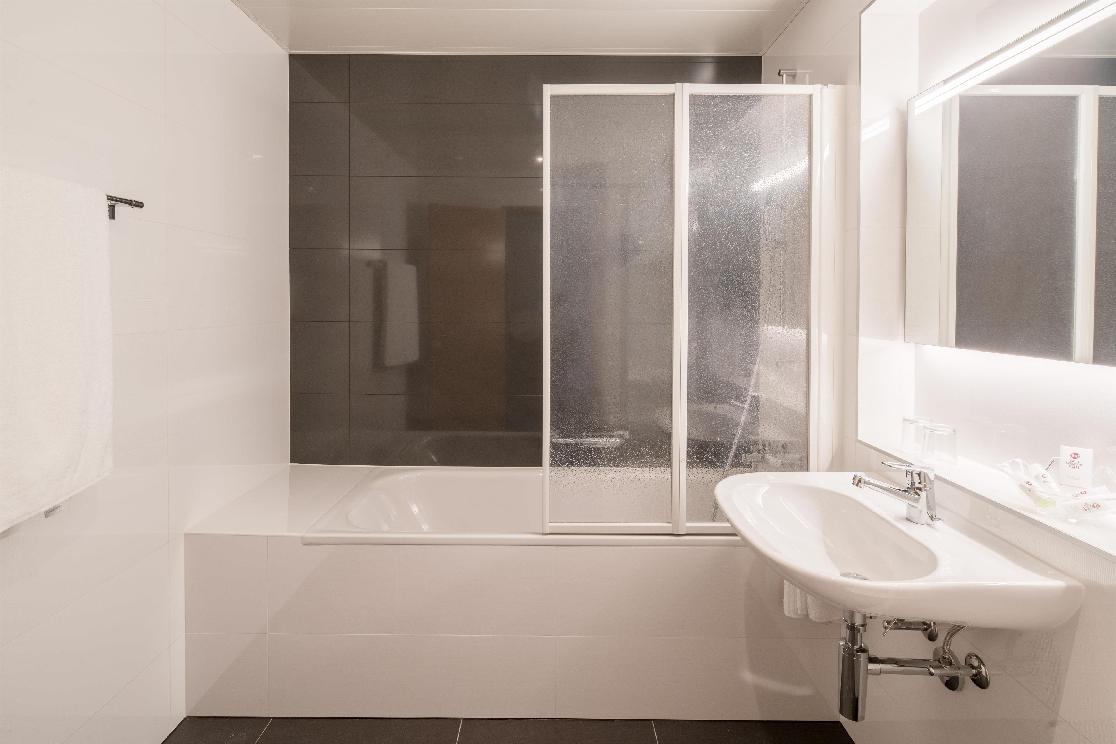 Une salle de bain moderne avec une baignoire, une douche à l’italienne et un lavabo avec un miroir.