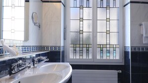 A bathroom with two sinks, a mirror, a window with a decorative grille, and a radiator. - Hotel Mirabeau, BW Signature Collection (Lausanne)