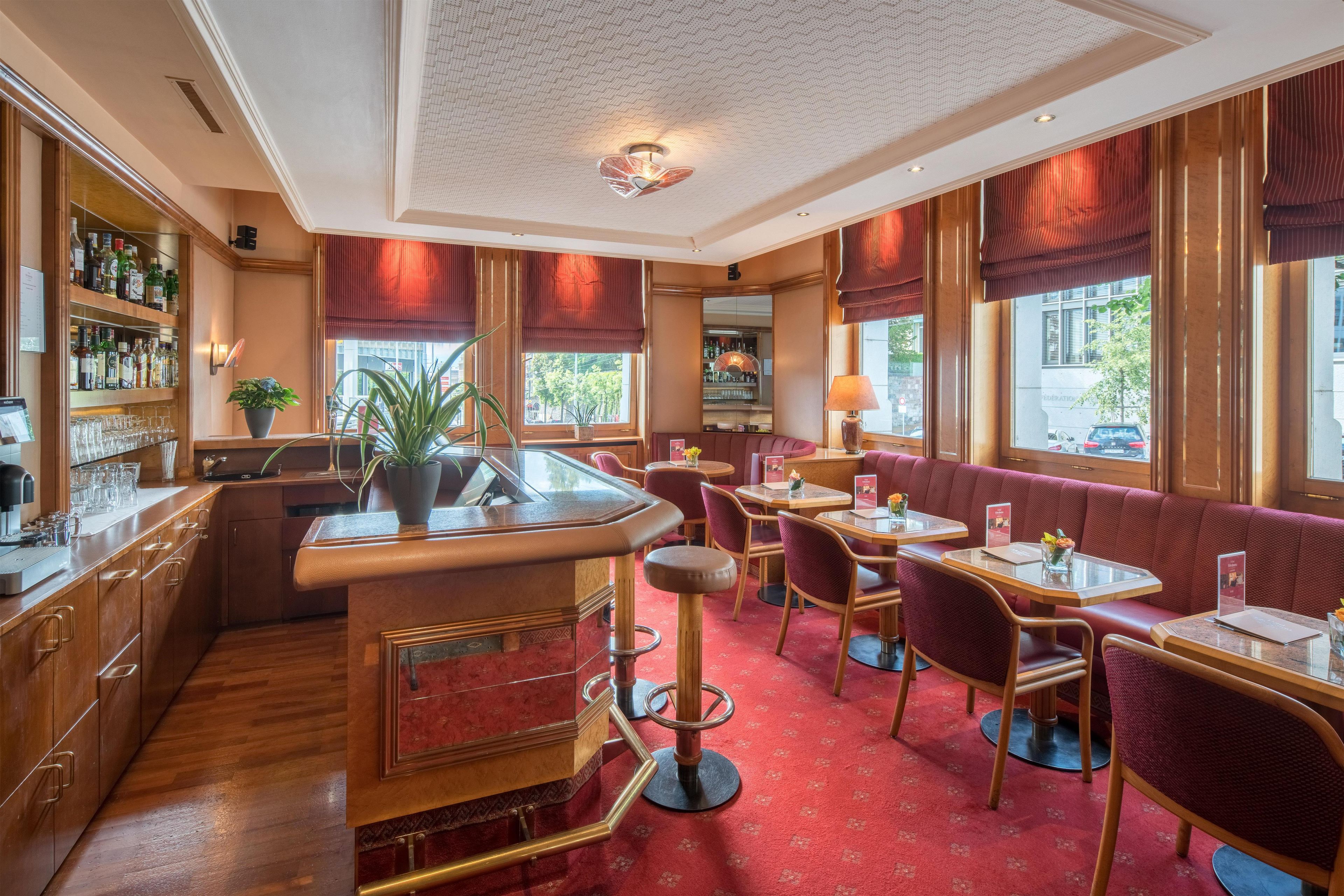 A bar area with a counter, shelves with bottles, and a seating area with tables and chairs.