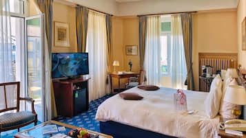 Une chambre d’hôtel comprenant un lit, une télévision, un bureau avec une chaise, une machine à café et une fenêtre avec des rideaux.