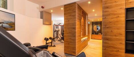 Un gimnasio moderno con equipo de ejercicio, paredes de madera y un ventanal grande.