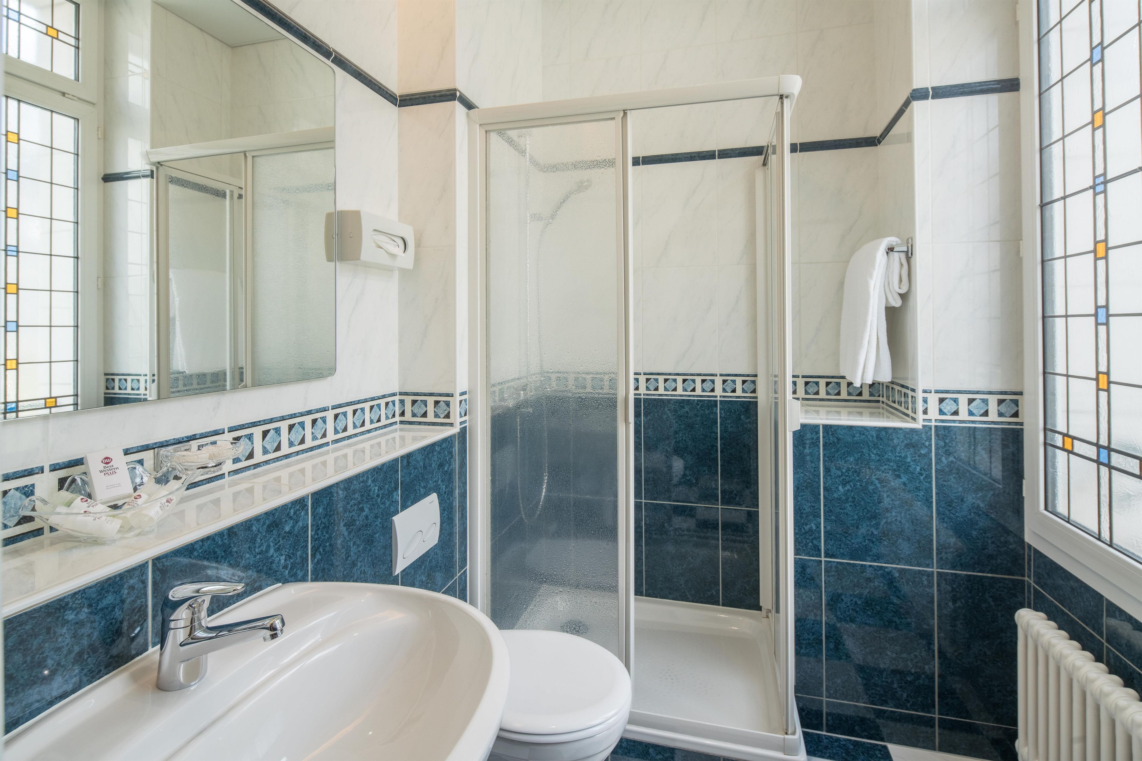 Un baño con lavamanos blanco, inodoro, ducha con cerramiento de vidrio y espejo.