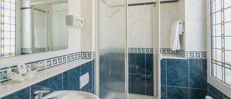 Un baño con lavamanos blanco, inodoro, ducha con cerramiento de vidrio y espejo.