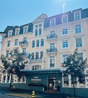 Un hotel de varios pisos con estilo arquitectónico clásico, que cuenta con balcones y una entrada destacada.