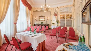 Ein formeller Esssaal mit einem langen Tisch, der für eine Mahlzeit gedeckt ist, umgeben von roten Stühlen und einer Büfettstation mit Snacks und Getränken.