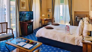 A hotel room with a large bed, a desk with a chair, a television, a coffee machine, and a window with curtains. - Hotel Mirabeau, BW Signature Collection (Lausanne)
