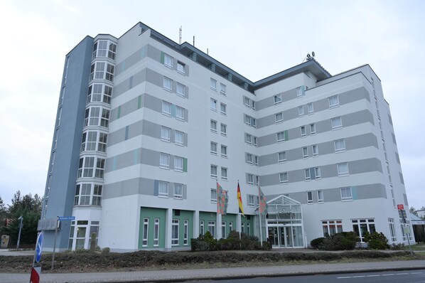 A multi-story hotel with a modern design, featuring a prominent entrance with glass doors and a green accent wall. - ACHAT Hotel Schwarzheide Lausitz (Schwarzheide)