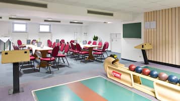 A conference room with a long table, red chairs, a whiteboard, and a bowling lane.