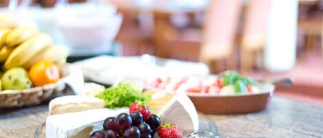 Una tabla de quesos con uvas y fresas sobre una encimera de mármol.