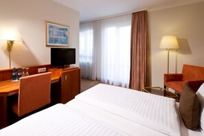 A hotel room with a bed, desk, TV, and two chairs. - ACHAT Hotel Schwarzheide Lausitz (Schwarzheide)
