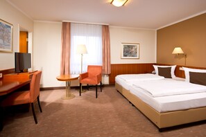 A hotel room with a bed, a desk with a chair, a lamp, and a painting on the wall. - ACHAT Hotel Schwarzheide Lausitz (Schwarzheide)