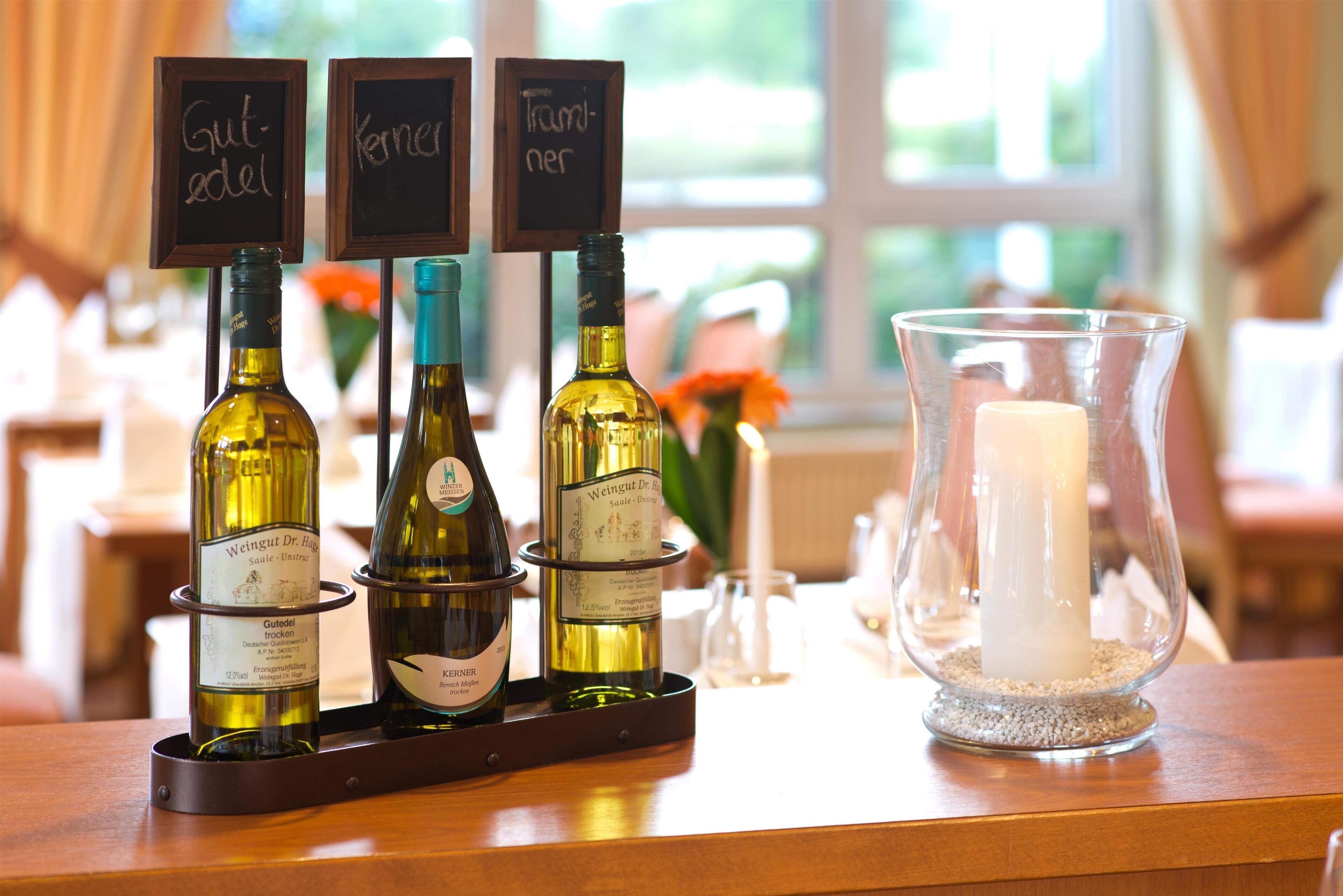 A selection of wine bottles on a tray with labels and a candle in a glass holder.