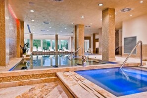 Una piscina techada, una piscina al aire libre, sombrillas