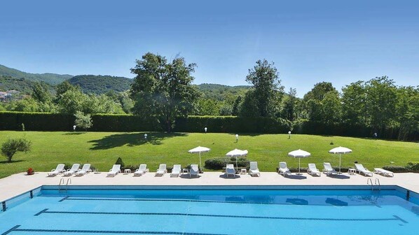 Alberca techada, alberca al aire libre y sombrillas en la alberca