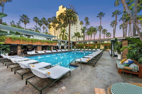 Una piscina al aire libre, sombrillas, sillones reclinables de piscina