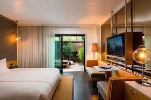 A hotel room with a bed, a desk with a lamp, a television, and a view of the outdoors.