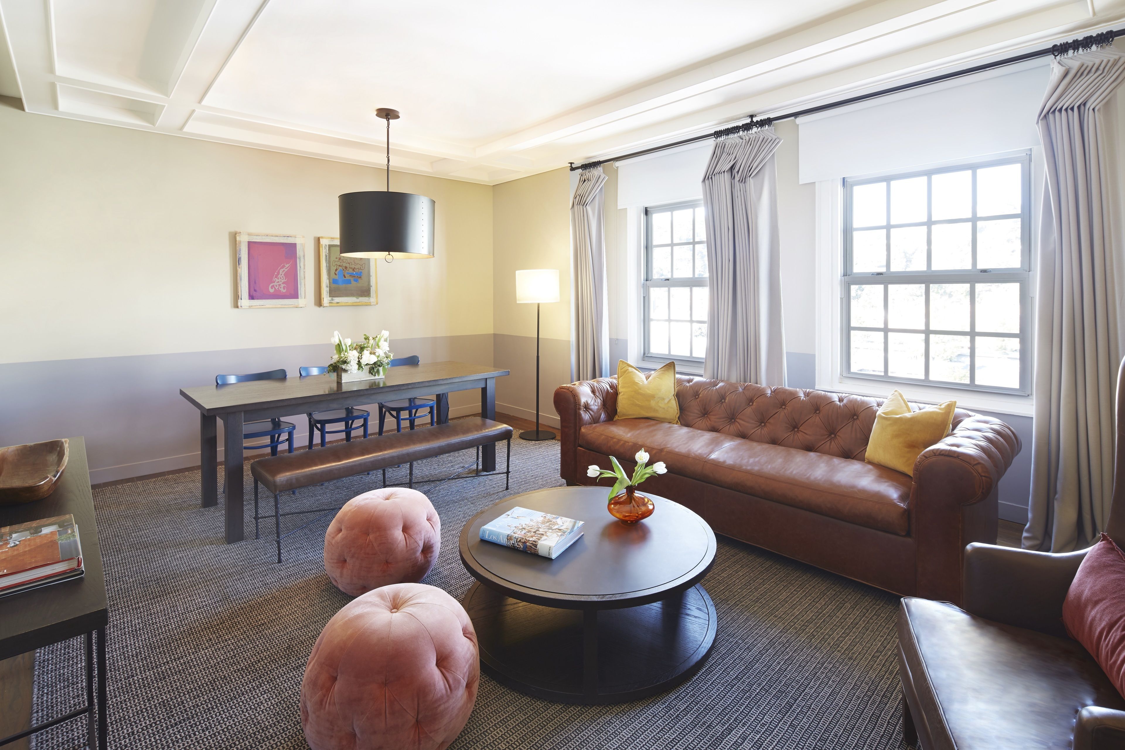 Un salon avec un canapé en cuir marron, une table basse ronde et un coin repas comprenant une banquette et une table.