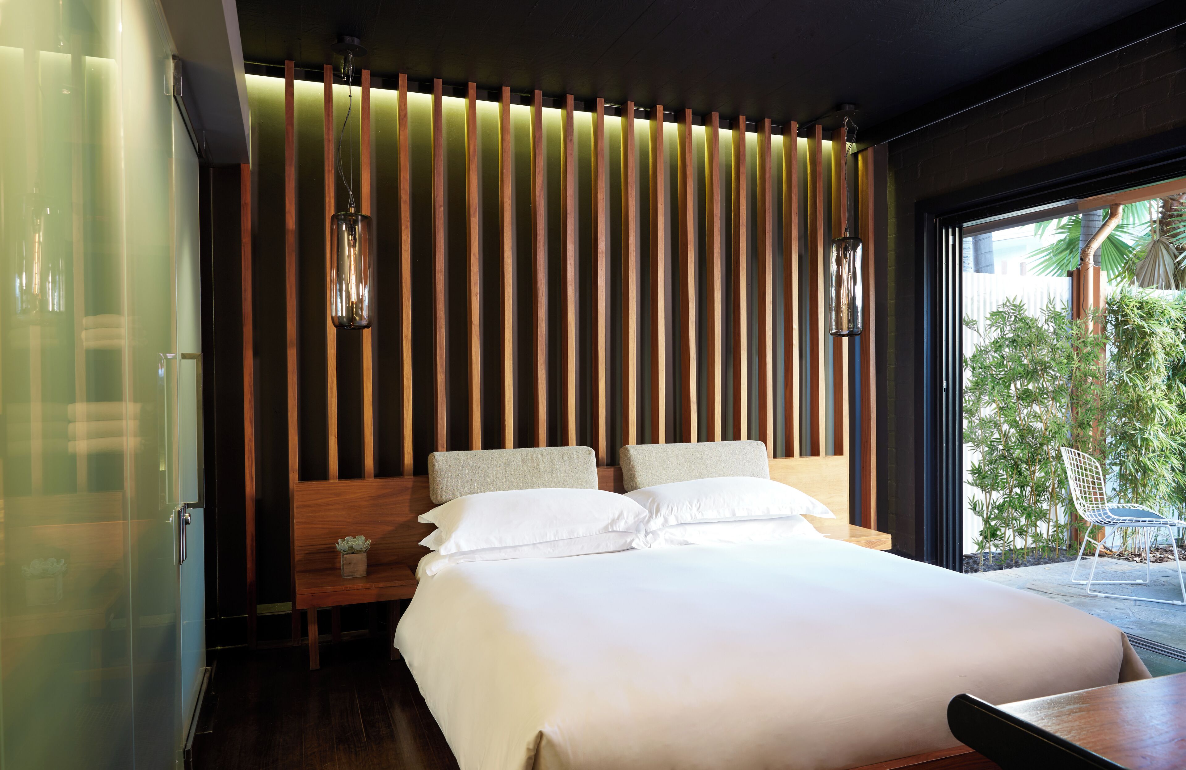 Une chambre d’hôtel moderne avec un grand lit, un mur en lambris de bois et une vue sur l’extérieur.