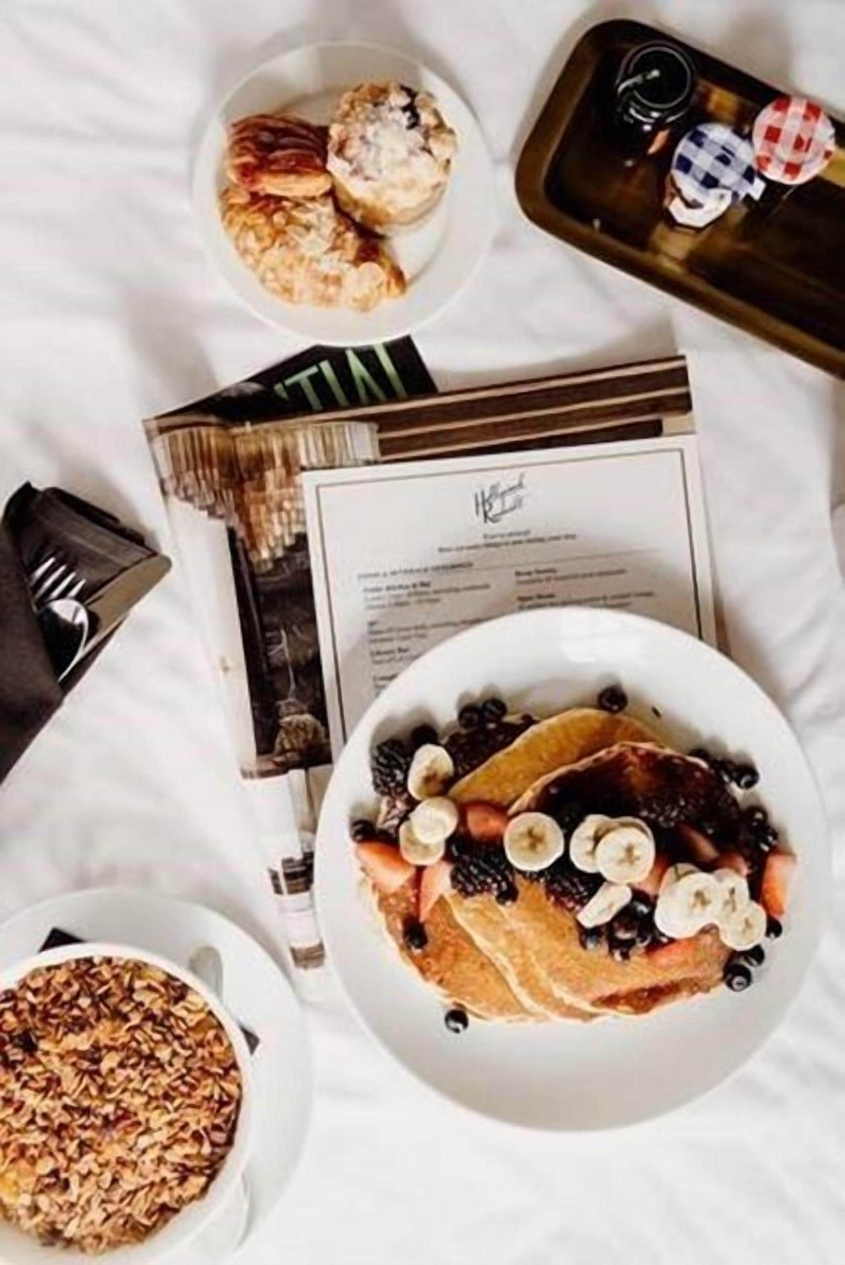A breakfast setting with pancakes topped with fruits and a side of granola.
