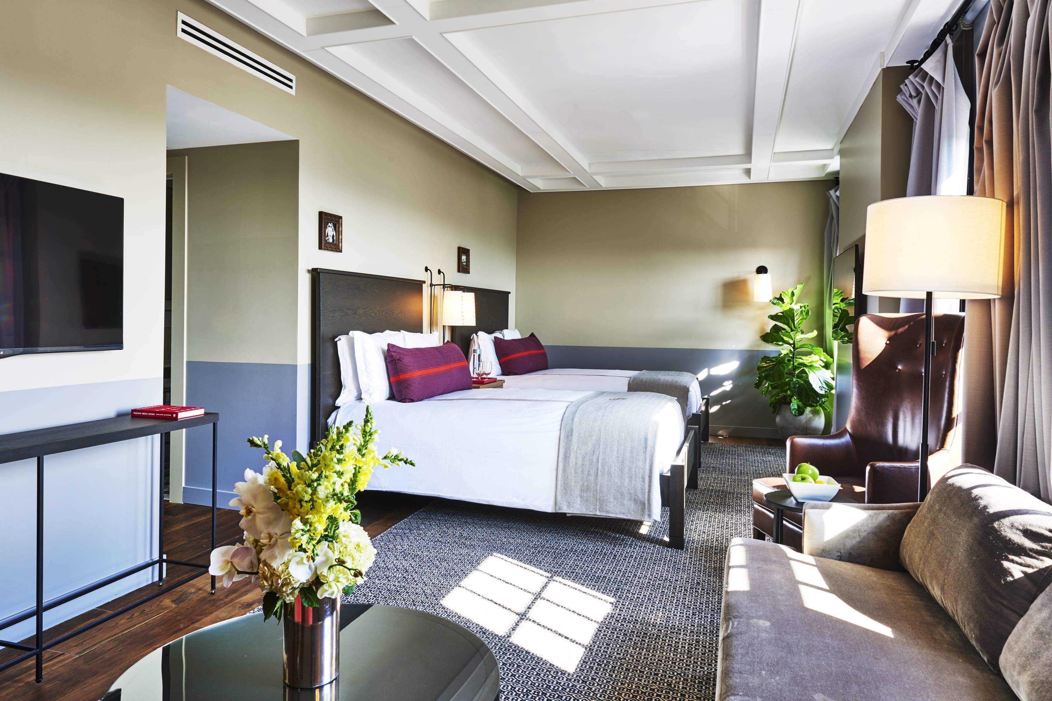 A hotel room with a bed, a desk, a sofa, a TV, and a lamp.