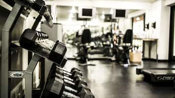 Uma academia com equipamentos de musculação, incluindo halteres e esteira.