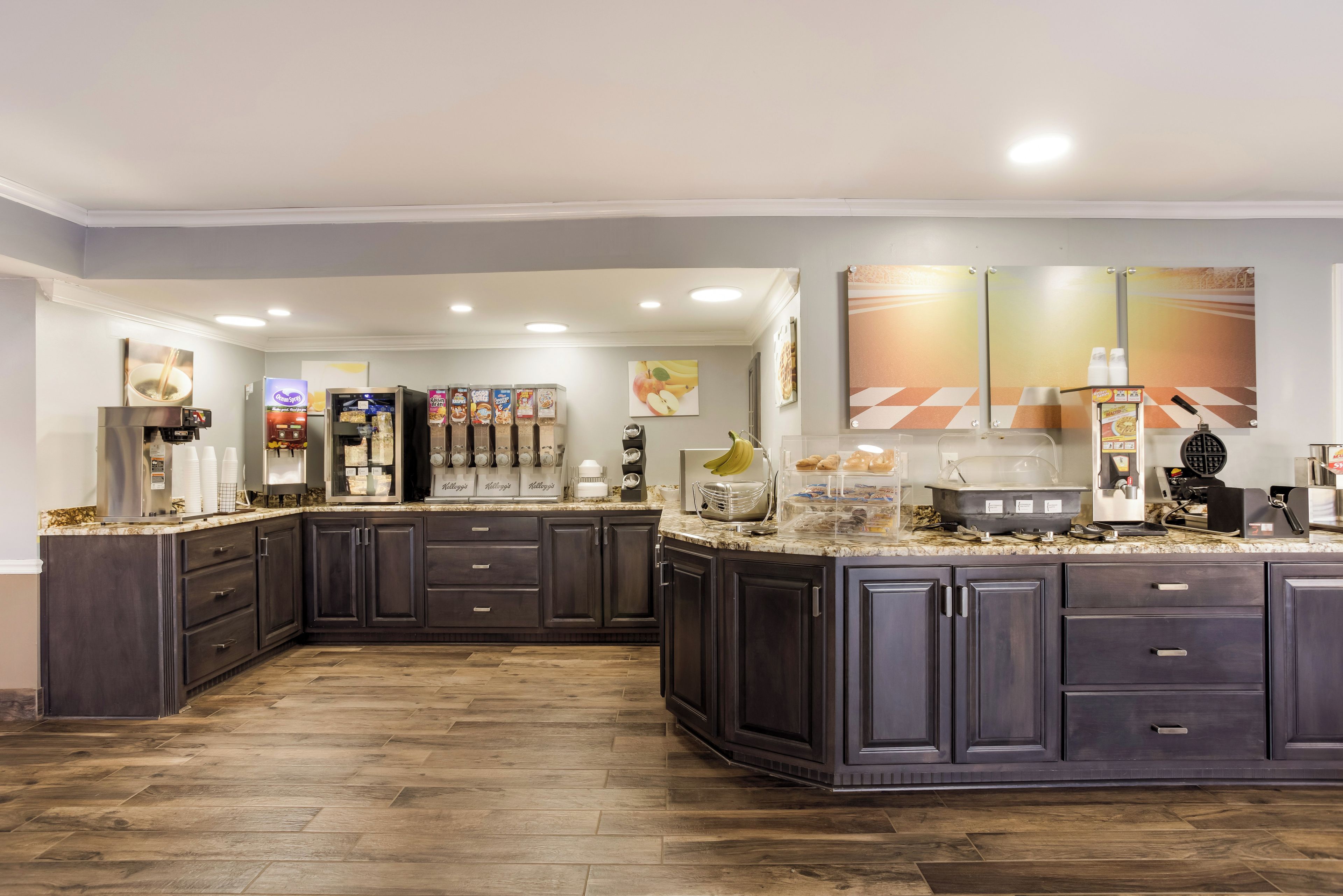 A modern kitchen with dark cabinetry, a marble countertop, and various appliances including a coffee machine and a waffle maker.