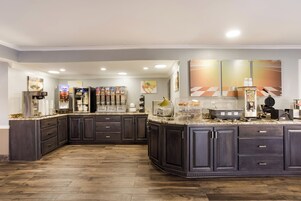 A modern kitchen with dark cabinetry, a marble countertop, and various appliances including a coffee machine and a waffle maker.