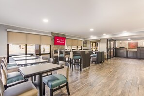 A restaurant with tables and chairs, a counter, and a sign indicating free Wi-Fi. - Red Roof Inn & Suites Athens, AL (Athens)