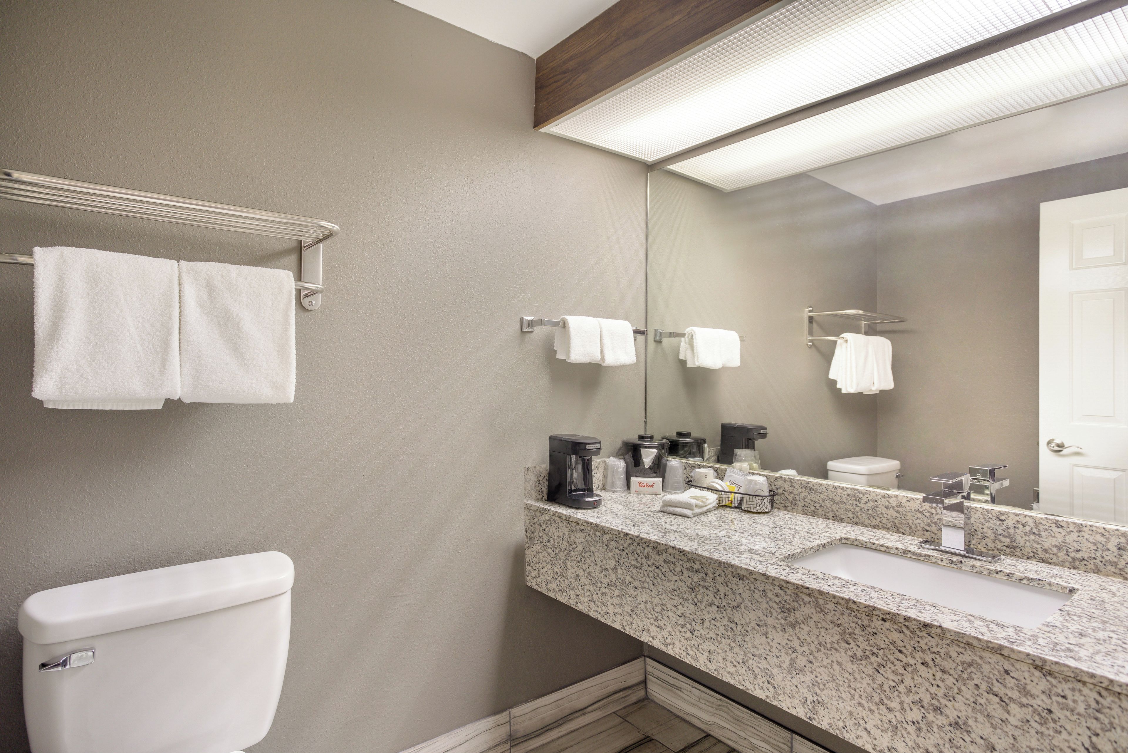 A bathroom with a toilet, a sink, a mirror, and towel racks.