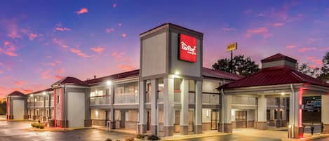 A Red Roof Inn & Suites with a two-story building, a covered parking area, and a clear sky.