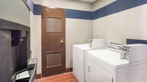 A laundry room with a brown door, a washing machine, and a dryer. - Red Roof Inn & Suites Athens, AL (Athens)