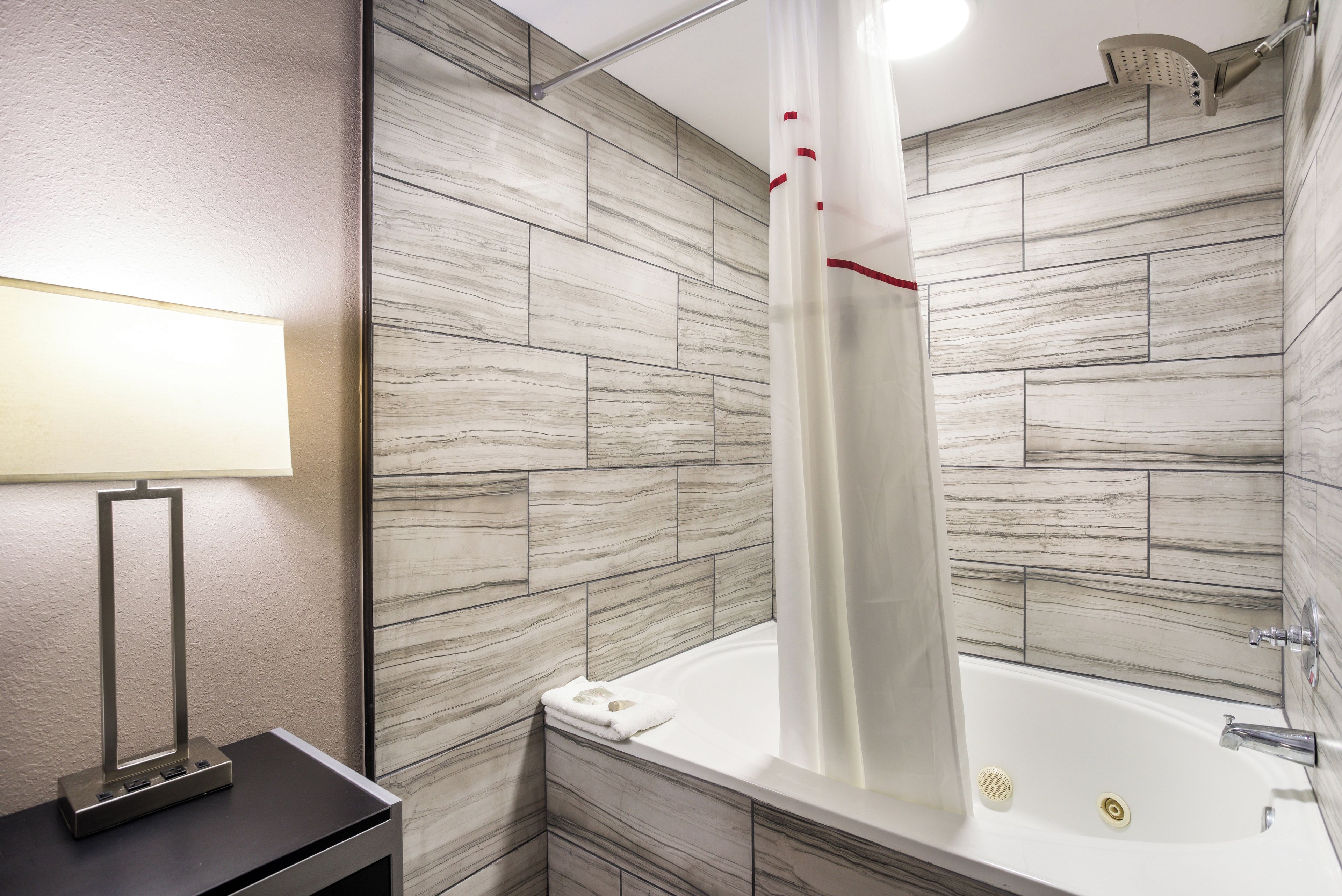 A modern bathroom with a bathtub, shower, and a towel rack.