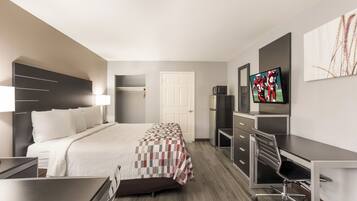 Habitación de hotel con cama, escritorio, silla, televisión y puerta.
