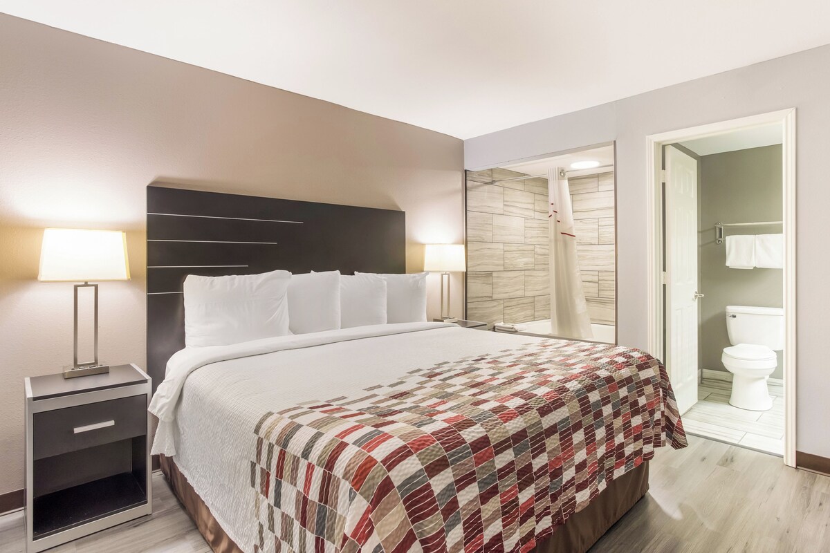 A hotel room with a bed, nightstand, and a bathroom visible through an open door.