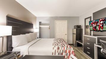 A hotel room with a bed, a TV, a desk, and a wardrobe.