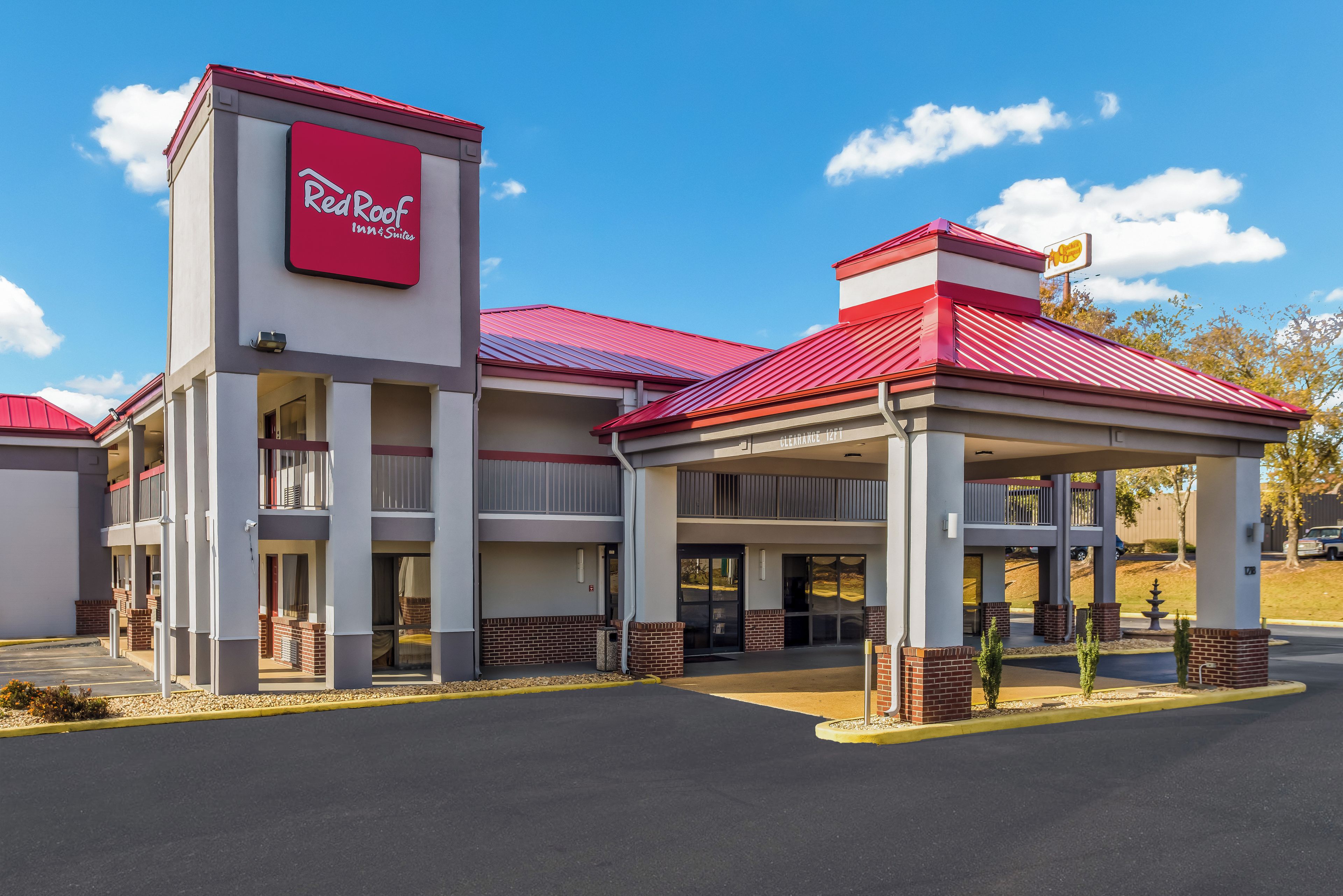 Un Red Roof Inn & Suites con entrada cubierta y un cielo azul despejado.