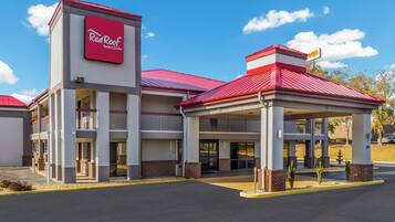 Un Red Roof Inn & Suites con entrada cubierta y un cielo azul despejado.
