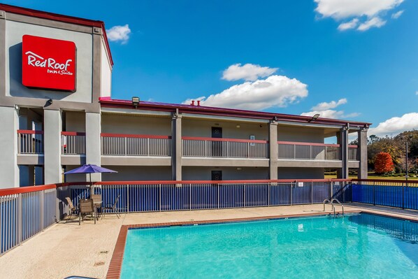 A Red Roof Inn & Suites with a swimming pool, outdoor seating, and a fenced balcony area. - Red Roof Inn & Suites Athens, AL (Athens)