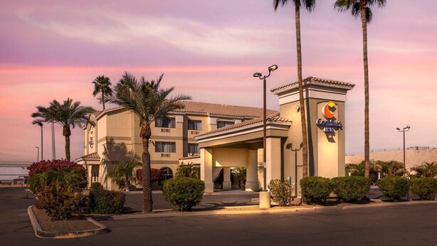 A hotel with a prominent sign, palm trees, and a parking lot. - Comfort Inn Phoenix Central City (Phoenix)