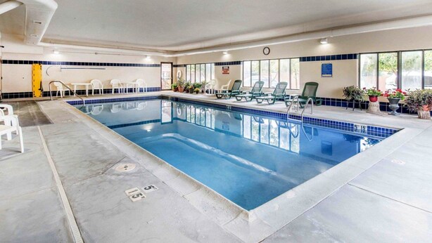An indoor swimming pool with clear water, surrounded by lounge chairs and potted plants. - Comfort Inn Salida (Salida)